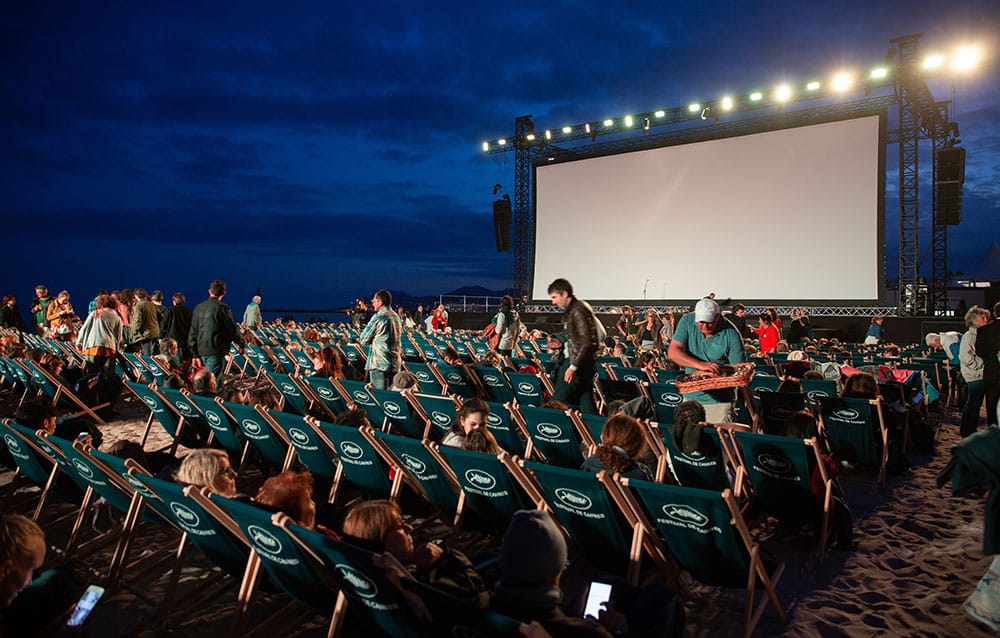 People watching a cinema screen on the beach at Cannes film festival