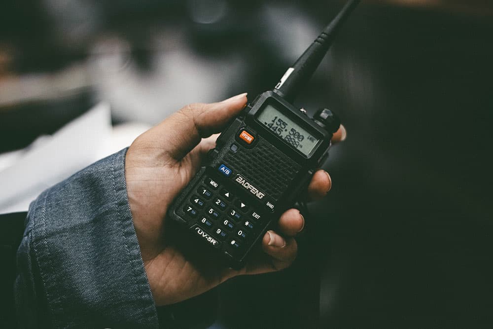 close-up of 1st AD holding a walkie talkie on set