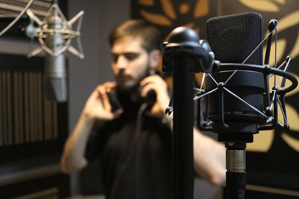 Actor standing in front of a microphone inside a recording studio
