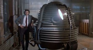 Seth Brundle stands beside his teleportation device in a laboratory