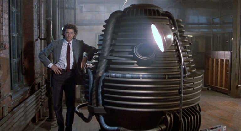 Seth Brundle stands beside his teleportation device in a laboratory