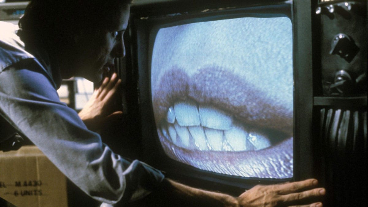 Max Renn leans toward a television screen displaying enlarged lips